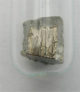 Die Seltene Erde Neodym hat eine Farbe von Silber bis Olivgrün. Sie liegt als kleiner Brocken, ähnlich wie ein Stein da.